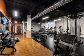 Cincinnati apartment for rent - a gym with cardio machines and weights on a wooden floor at Textile Apartments, Cincinnati, Ohio