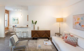 Hollywood apartment for rent - A living room with a white couch, a grey chair, a coffee table, and a painting on the wall.