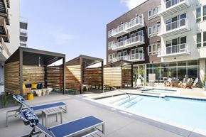 Denver apartment for rent - a swimming pool with chairs and tables in front of an apartment building