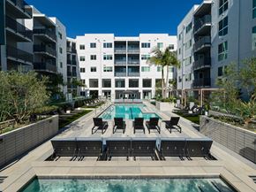 Los Angeles apartment for rent - a swimming pool with chairs in front of an apartment building