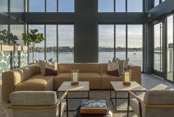 Oakland apartment for rent - a living room with a view of the water and a couch and tables