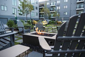 A fire pit surrounded by rocking chairs in a courtyard
