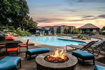 A swimming pool with a fire pit and chairs around it