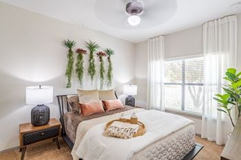 A bedroom with a bed, nightstands, and a window.