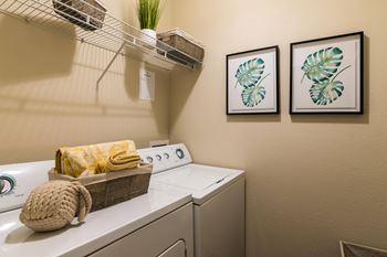 A small room with a washing machine and a basket on top of it.