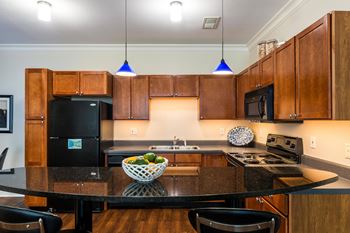 A kitchen with a black fridge and a bowl of fruit on the counter.