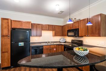 A kitchen with wooden cabinets and a black fridge.