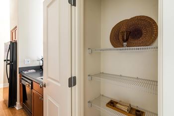 A kitchen with a stove and a hat on the shelf.