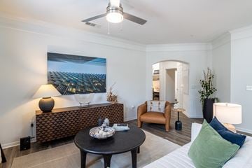 Katy apartment for rent - A living room with a brown patterned bench and a painting of a palm tree on the wall.