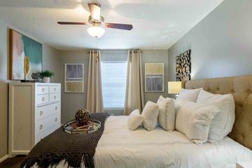 Lenexa apartment for rent - A bedroom with a large bed and a ceiling fan.