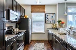 Carmel apartment for rent - A kitchen with black cabinets and granite countertops. at Penn Circle, Carmel