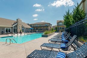 Shawnee apartment for rent - A row of blue and white striped lounge chairs line the edge of a swimming pool.