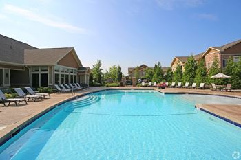 A swimming pool with lounge chairs and buildings in the background