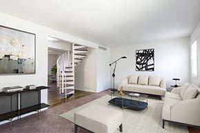 Springfield townhouse for rent - A living room with a white couch, a black coffee table, and a spiral staircase at Spring Creek Townhomes Apartments, Springfield, IL 62702