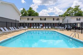 Springfield townhouse for rent - A large swimming pool in front of a building with lounge chairs around it at Spring Creek Townhomes Apartments, Springfield, IL
