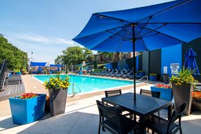 Roeland Park apartment for rent - A poolside table with chairs and umbrella overlooking a pool.