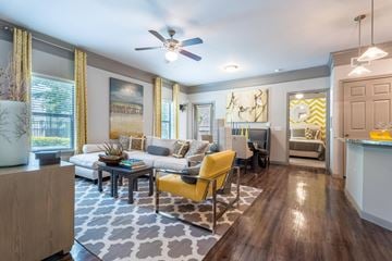 Katy apartment for rent - A living room with a yellow chair and a grey and white patterned rug.