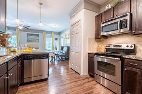 Katy apartment for rent - A kitchen with dark wood cabinets and stainless steel appliances at Waterstone at Cinco Ranch Apartments, Katy Texas