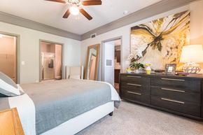 Katy apartment for rent - A bedroom with a bed, dresser, and a ceiling fan at Waterstone at Cinco Ranch Apartments, Katy Texas