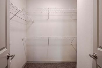 A walk in closet with empty shelves in a white room