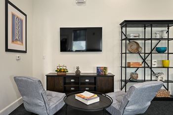 A living room with two chairs and a table and a television