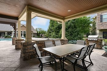 A covered patio with a table and chairs and a pool