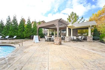 A patio with a pool and chairs and a pavilion