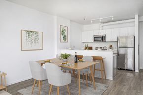 Portland apartment for rent - Studio Apartments in Southeast Portland, OR - The Lenox - Dining Area with a 4-Piece Dining Set, Luxury Wood Grain Vinyl Plank Flooring, and White Kitchen