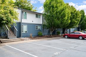 Salem apartment for rent - A red car is parked in a parking lot in front of a two-story building.