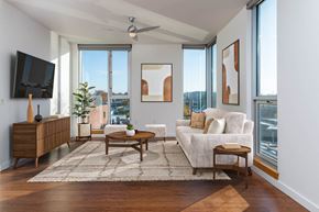 Portland apartment for rent - A living room with a white couch, a wooden coffee table, and a flat screen TV mounted on the wall.