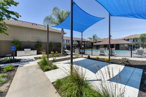 Modesto apartment for rent - Exterior Courtyard with sunshade over concrete pad. Pathway leading to outdoor BBQ area.