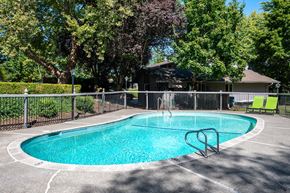 Tigard apartment for rent - a pool with a fence around it and a house in the background