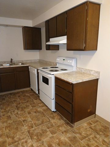 Albany apartment for rent - A kitchen with brown cabinets and a white stove top oven.