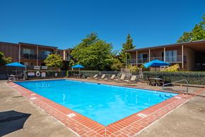 Portland apartment for rent - outdoor pool with seating around and blue umbrellas over tables.
