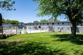 Hermiston townhouse for rent - A large tree is in the foreground of a grassy area in front of a building.