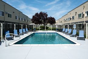 Pasco apartment for rent - A swimming pool surrounded by chairs and a tree in a sunny courtyard.