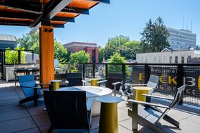 Eugene apartment for rent - a rooftop patio with tables and chairs and a building in the background