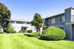 Kennewick apartment for rent - the exterior of an apartment building with a lawn and bushes