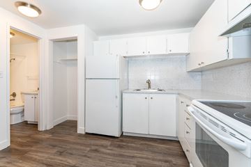 Shoreline apartment for rent - A kitchen with white cabinets and a wooden floor.