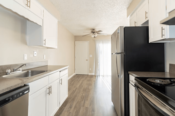 Salem apartment for rent - A black refrigerator stands in a kitchen with white cabinets and a sink.