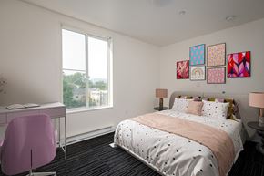 Eugene apartment for rent - A bedroom with a large bed, a desk with a chair, and a window with a view of the outdoors.
