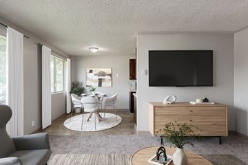 Springfield apartment for rent - A modern living room with a grey sofa, a white dining table and chairs, a wooden cabinet, and a flat-screen TV mounted on the wall.