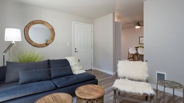 Tukwila apartment for rent - A living room with a blue couch and a round mirror on the wall.