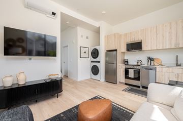 Vancouver apartment for rent - A modern living room with a black sofa and a wooden cabinet.