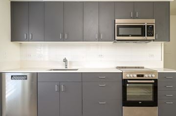 Bend apartment for rent - A kitchen with a stainless steel refrigerator, a microwave, and a stove top oven.