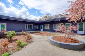 Hillsboro apartment for rent - the front of a blue building with a pathway and a tree in front of it