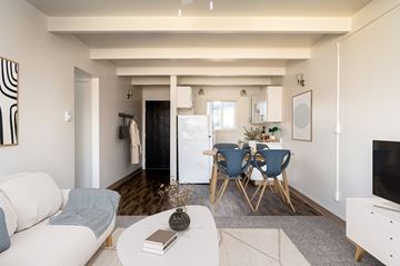Portland apartment for rent - A living room with a white sofa, a grey rug, a white coffee table, a blue chair and a white cabinet.