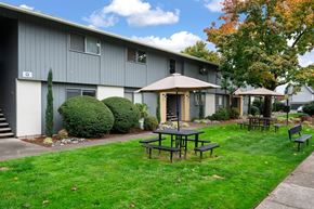 Springfield apartment for rent - A grey building with a patio table and chairs in front of it.