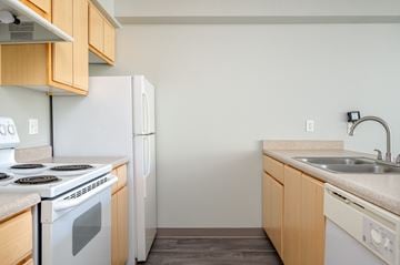 Corvallis apartment for rent - A kitchen with a white stove and white refrigerator with wooden cabinets.