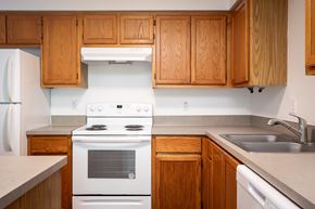 Eugene apartment for rent - A kitchen with wooden cabinets and a white stove top oven.
